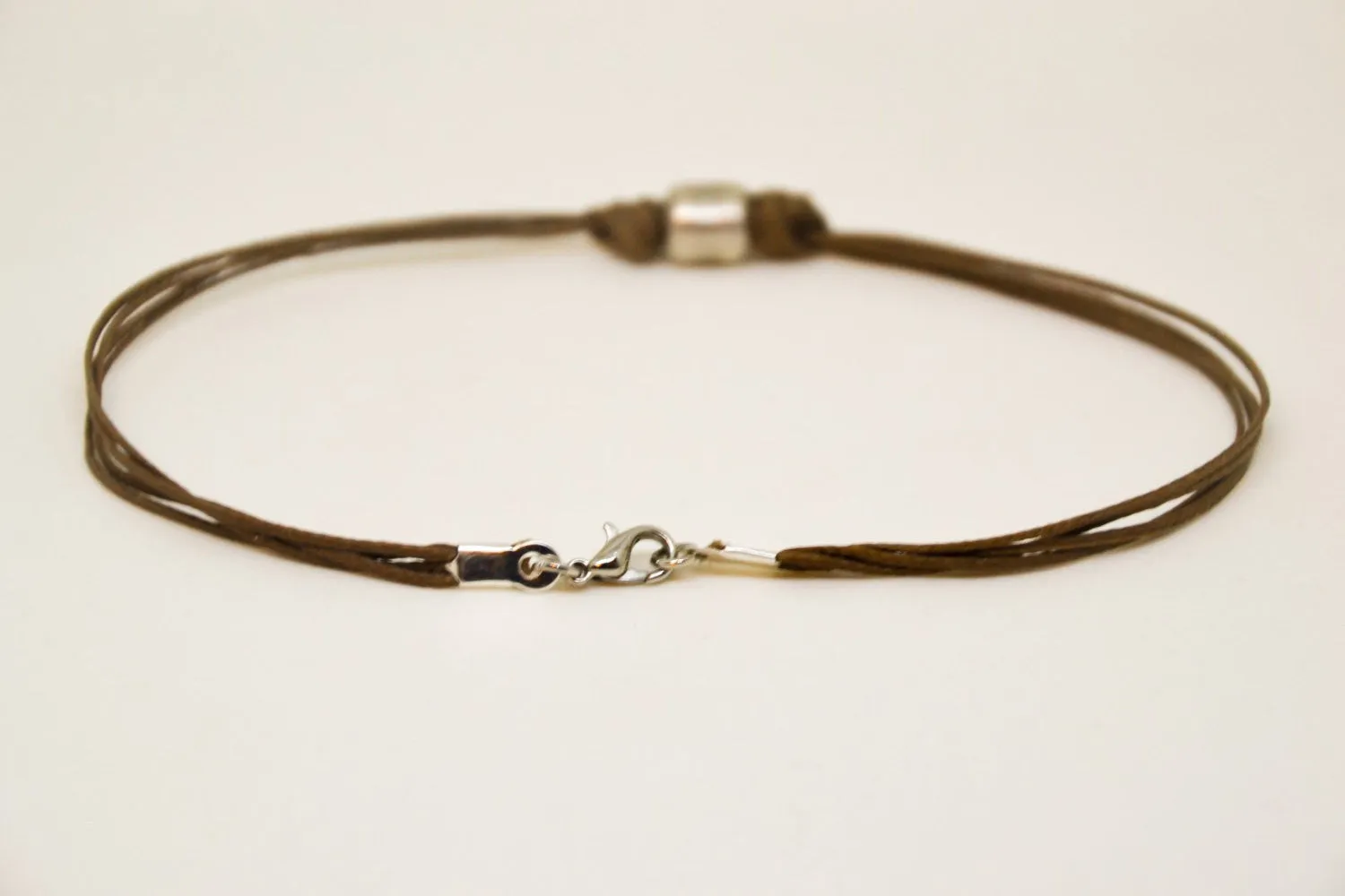 Men's anklet with a silver tube charm and a brown cord, jewelry for man